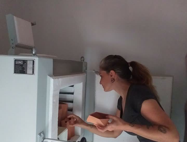 Flavia organizando peças no forno elétrico do ateliê.