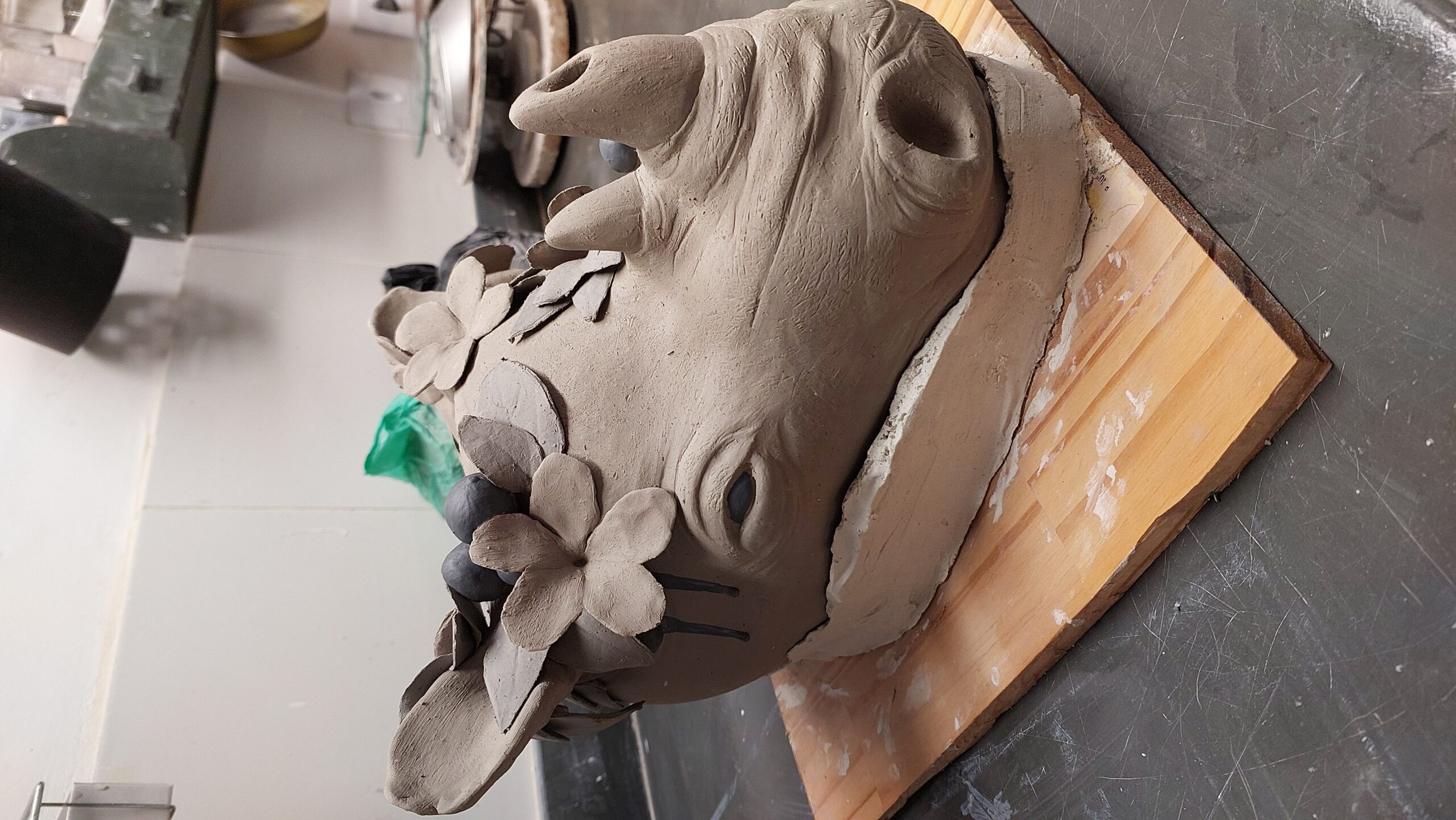 Cabeça de rinoceronte em modelagem sobre uma base de madeira no ateliê.